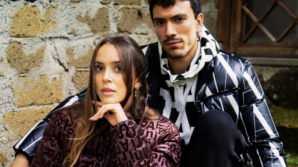  Modello e modella indossano piumini firmati Armani Exchange, parte della collezione autunno-inverno 2024, con stampe geometriche e loghi in evidenza.